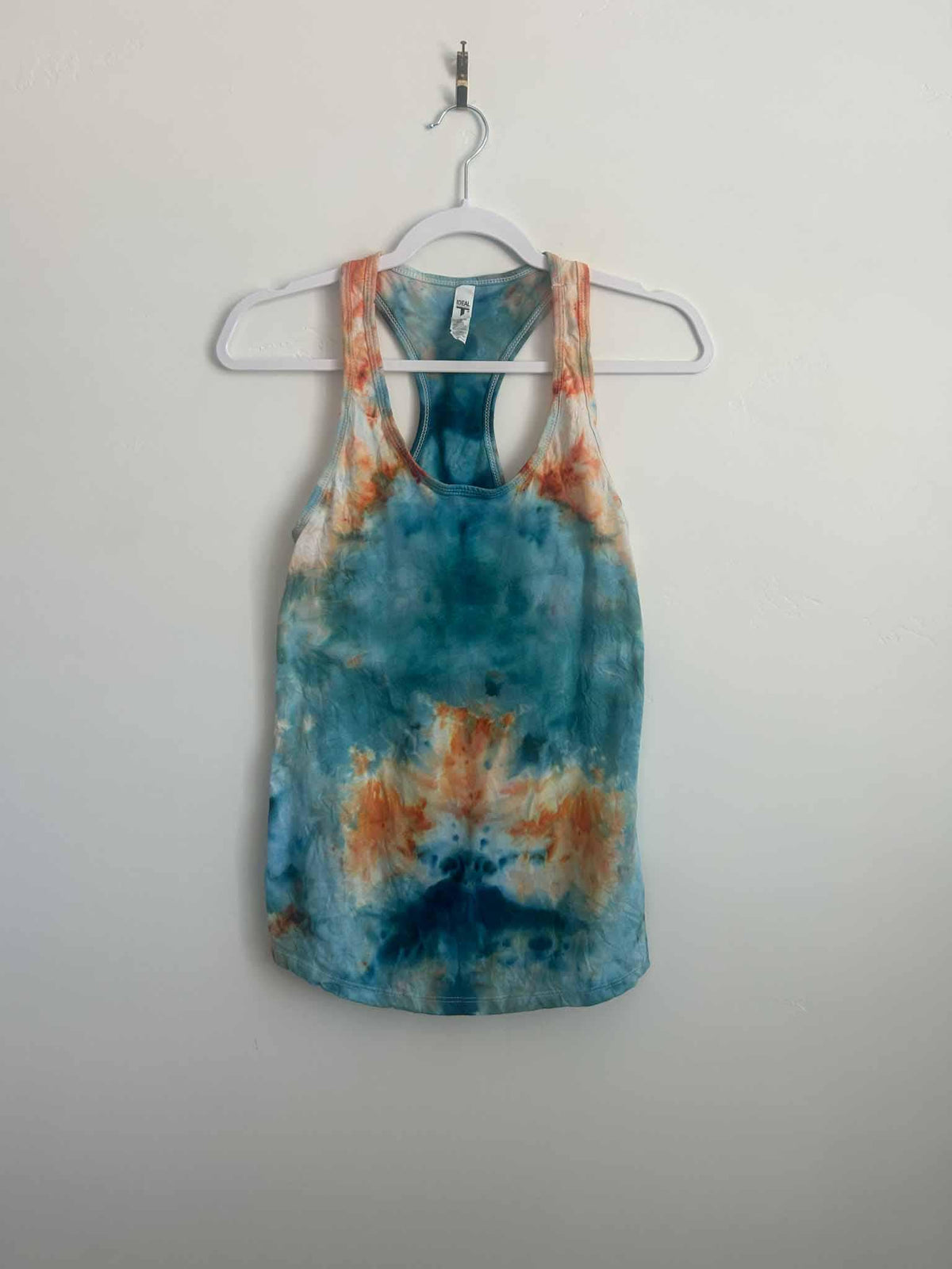 Ice dye mirror fold tank top in kingfisher blue and peach, full front view on hanger