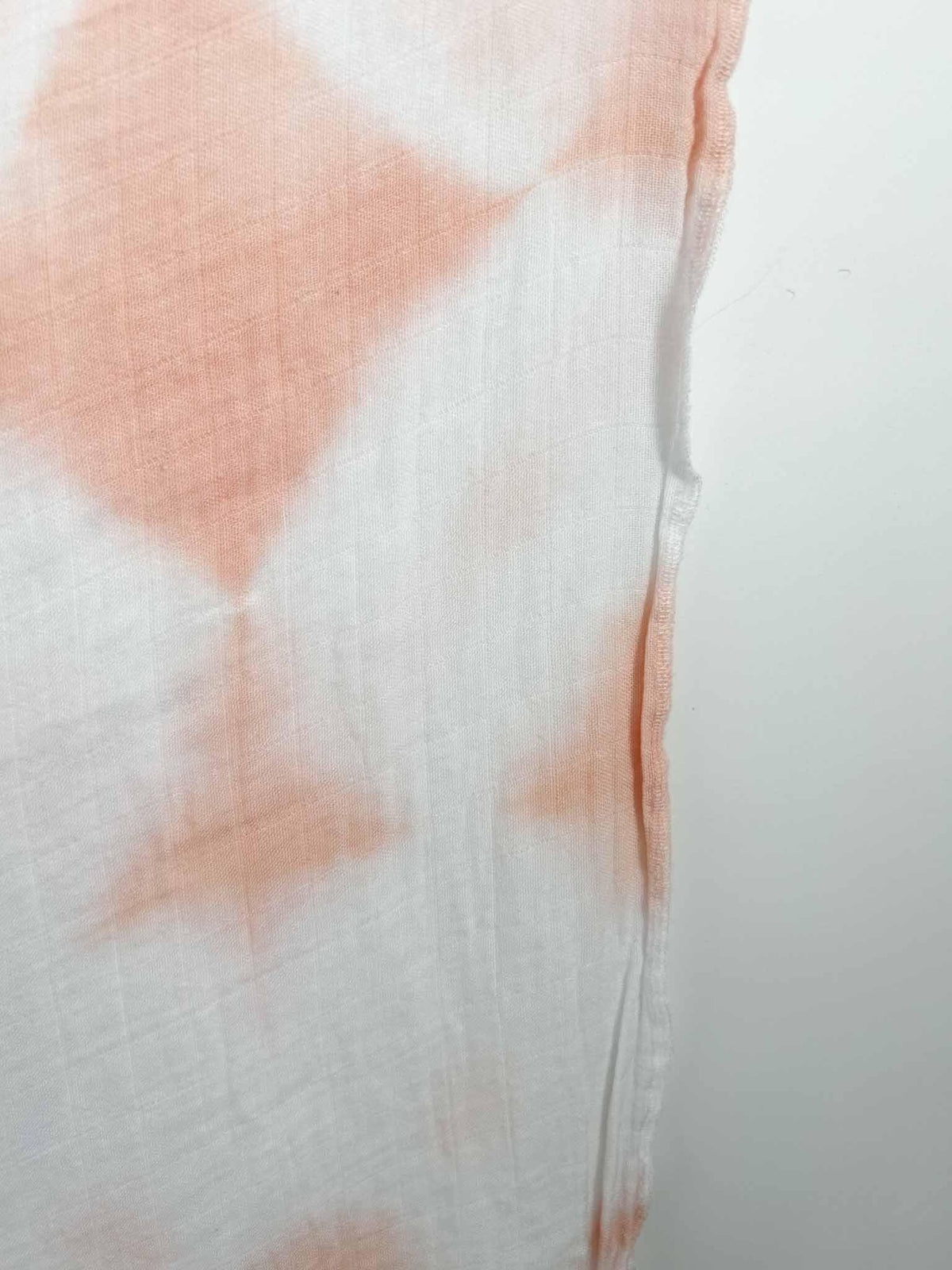 Close up of peach shibori diamond pattern on bamboo cotton gauze fabric showing texture and hem