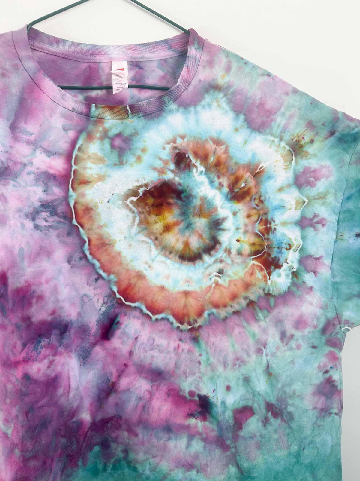 Close up of rust and sky blue geode swirl centered on purple and teal tie dye shirt