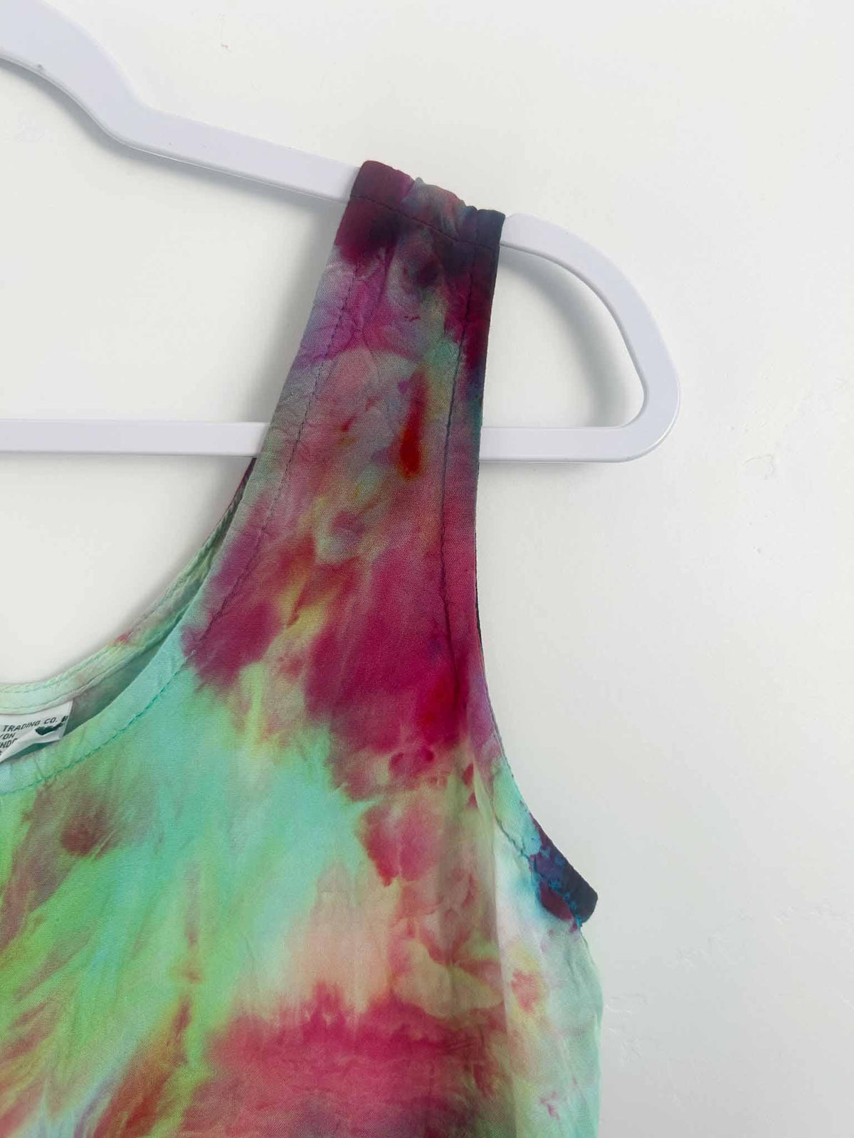 Close-up of ice dye rayon dress shoulder strap in magenta and mint tie dye