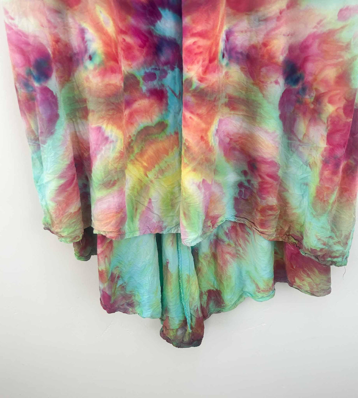Close-up of ice dye hi-lo dress hem showing rainbow and aqua underlayer
