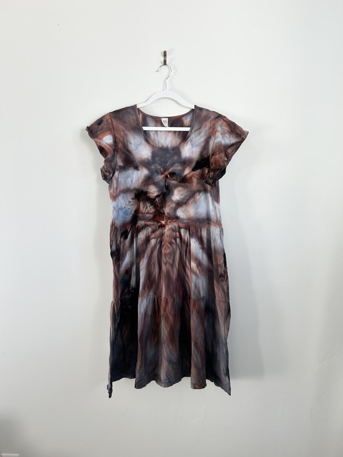 Rust brown and charcoal ice dye tiered dress hanging on white hanger, full front view