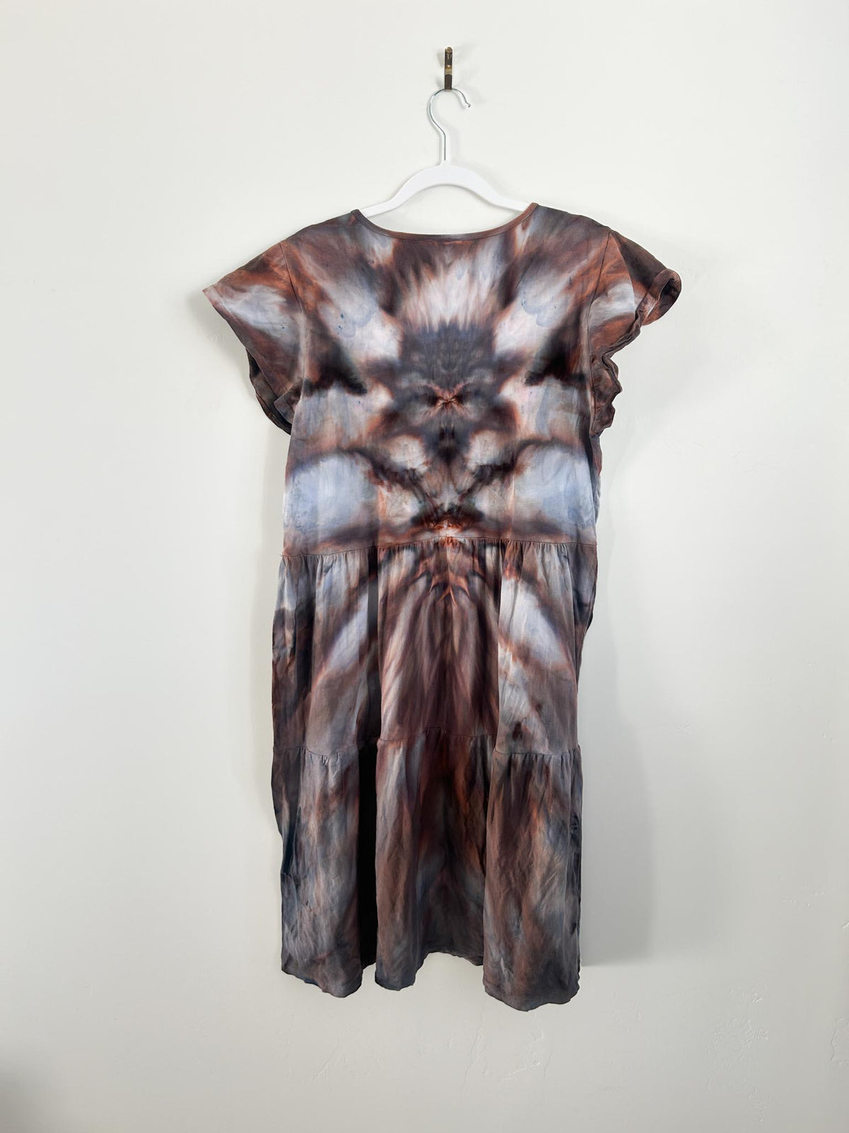 Back view of rust brown and charcoal tie dye tiered dress on hanger