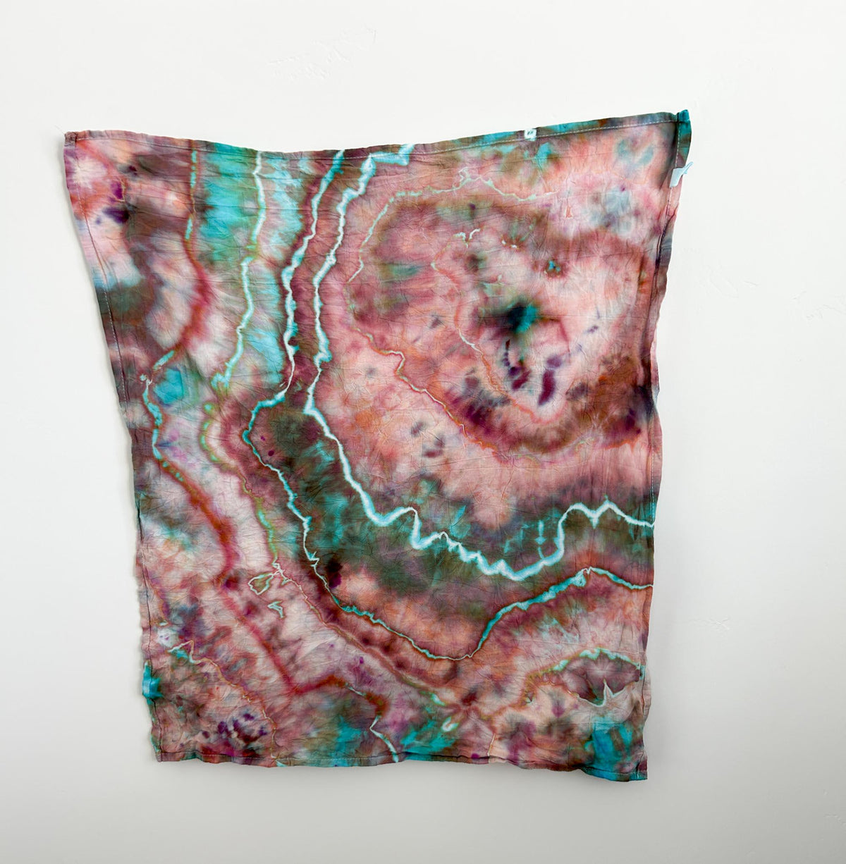Ice dyed cotton tea towel hanging flat, full view of rose turquoise marbled pattern