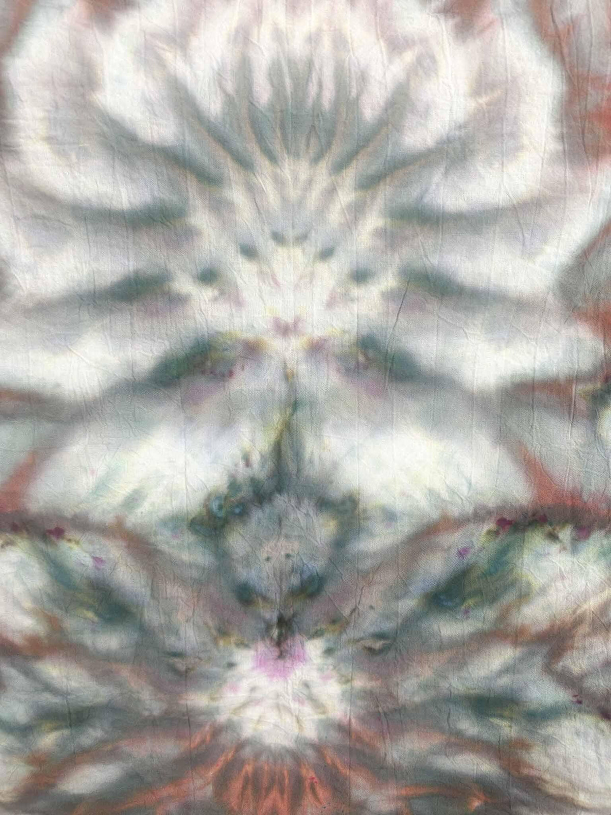 Close up of dusty rose and sage green ice dye kaleidoscope pattern on cotton tea towel