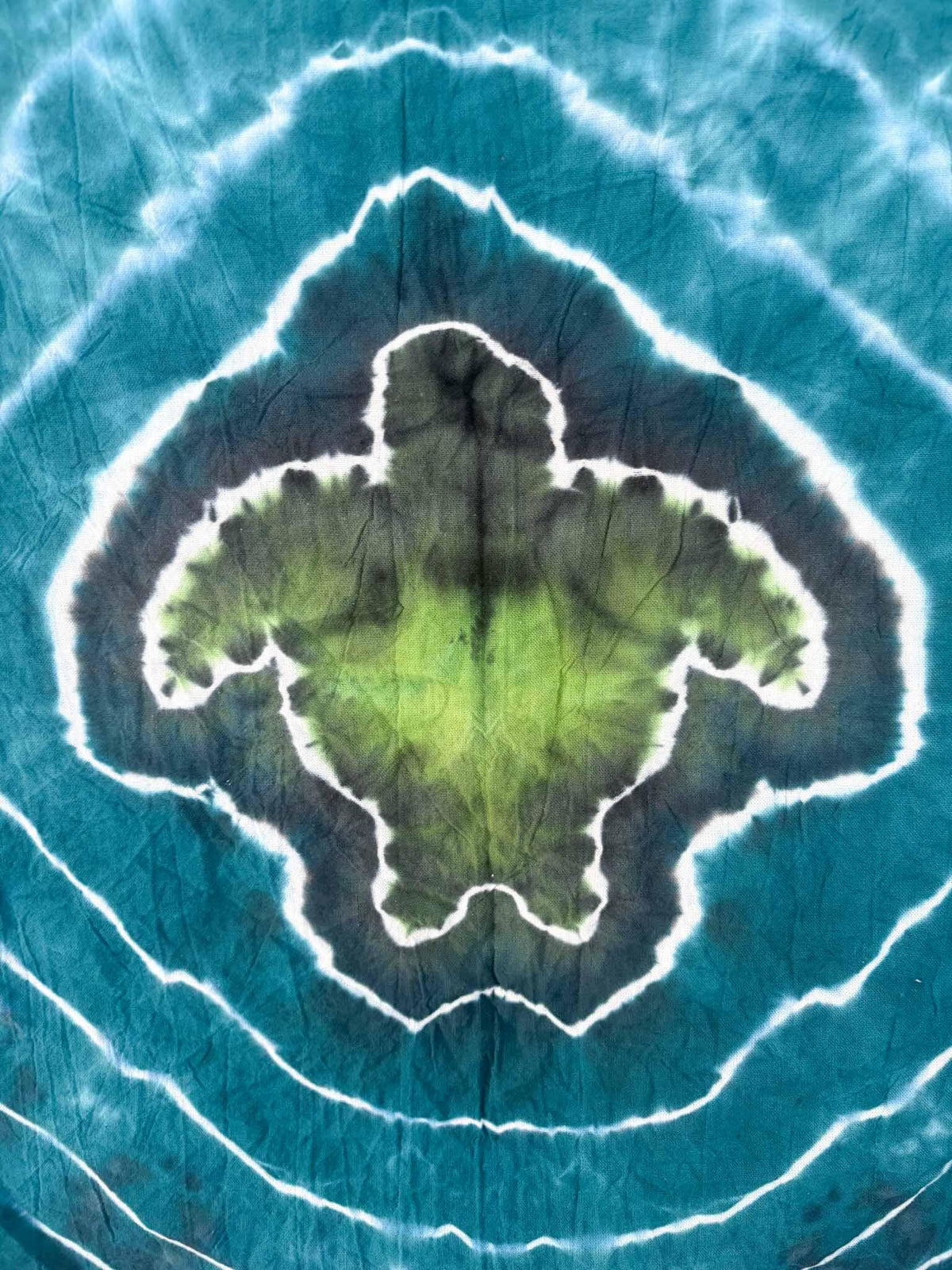 Close-up of green sea turtle tie dye design with teal ripple pattern
