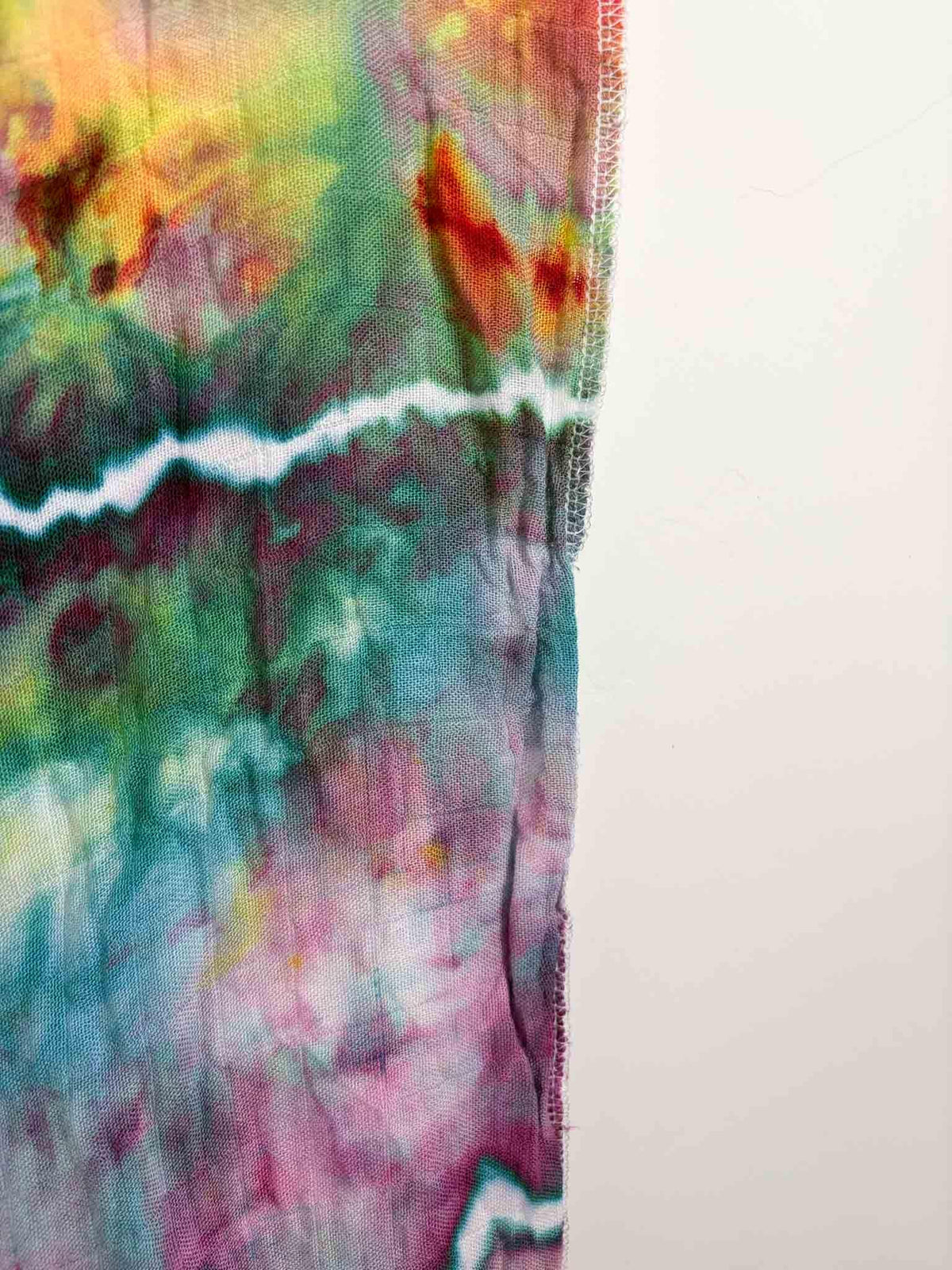 Close up of serged edge on hand dyed bamboo gauze swaddle showing geode crystal line detail in teal and pink