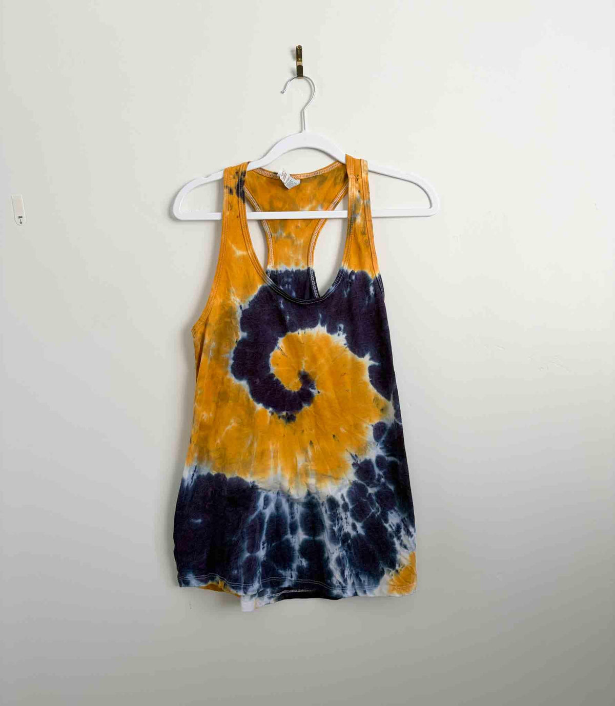 Mustard yellow and navy purple spiral tie dye racerback tank top on white hanger