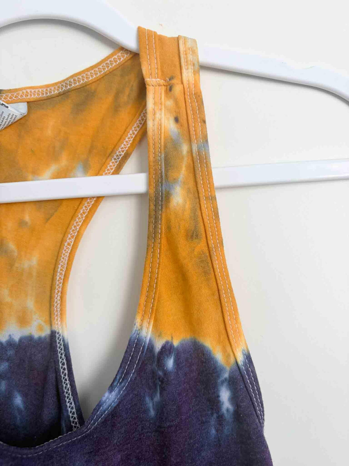 Close up of racerback strap on mustard and navy tie dye tank showing dye saturation