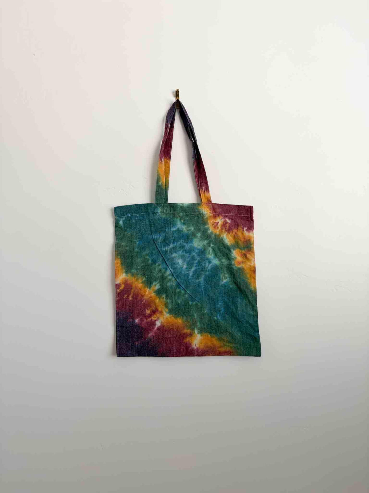 Teal, gold, and magenta tie dye tote bag hanging, 100% cotton canvas with long handles