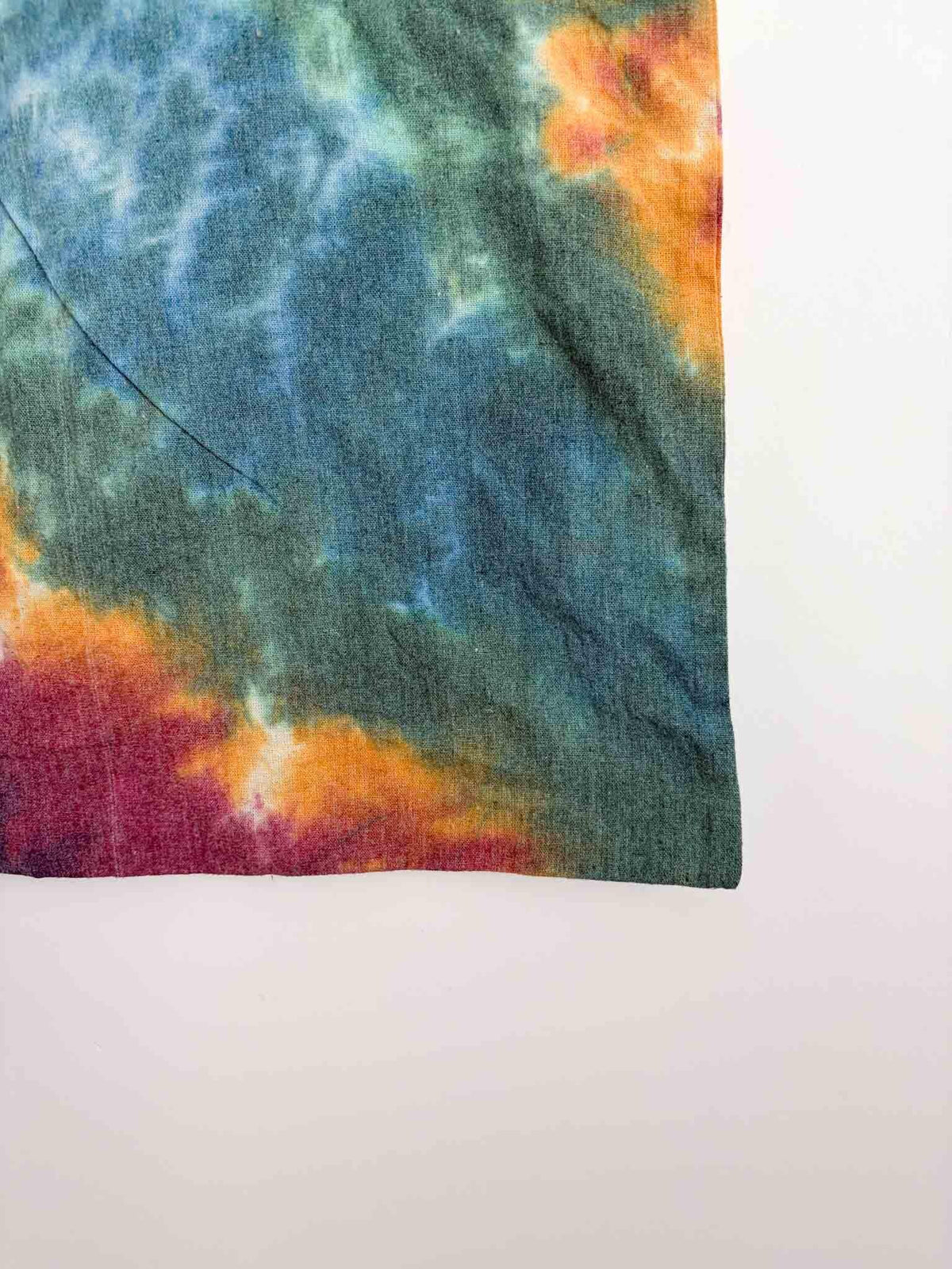 Close up of teal and gold tie dye pattern on cotton canvas tote bag showing color blend