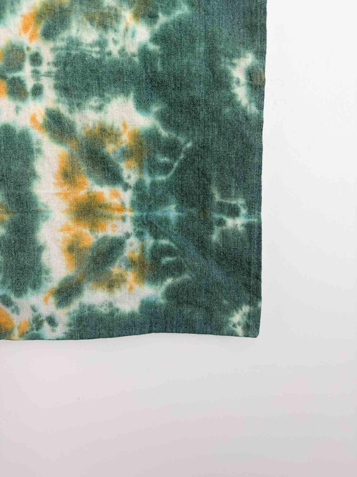 Close up of shibori tie dye pattern on cotton canvas tote bag in green and gold tones
