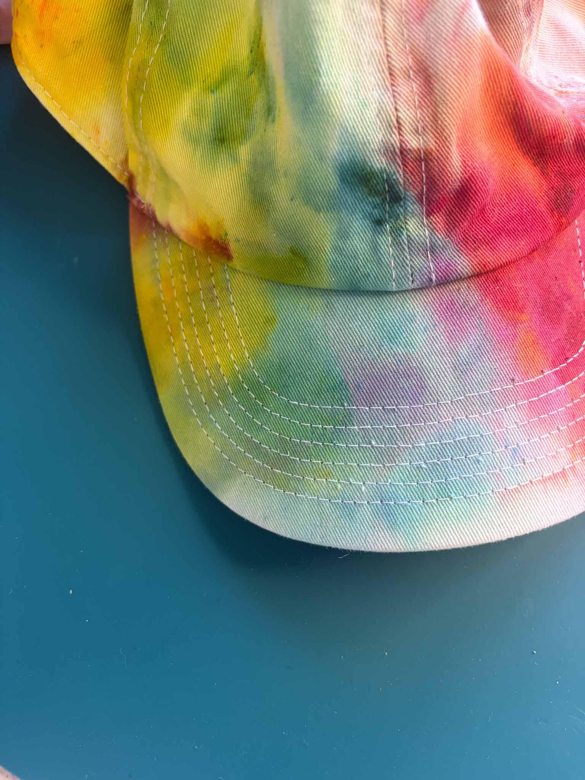 Close up of yellow pink and green tie dye dad hat brim and bill