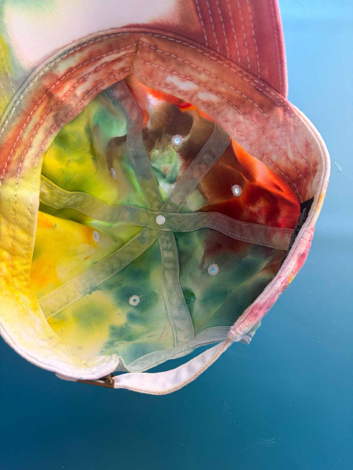 Inside crown of rainbow ice dye baseball cap showing colorful underside