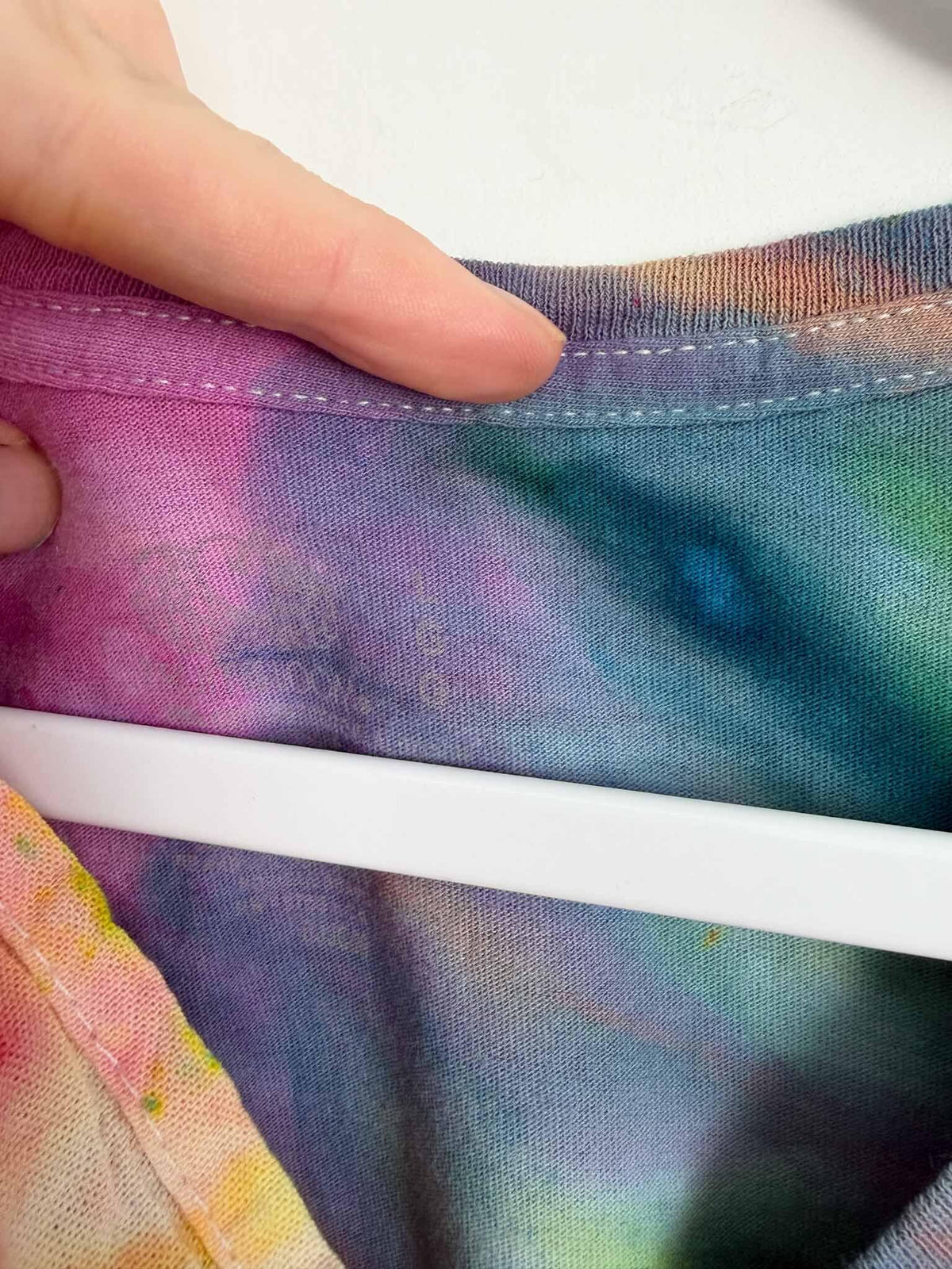 Neckline detail of rainbow tie dye v-neck shirt showing color blend