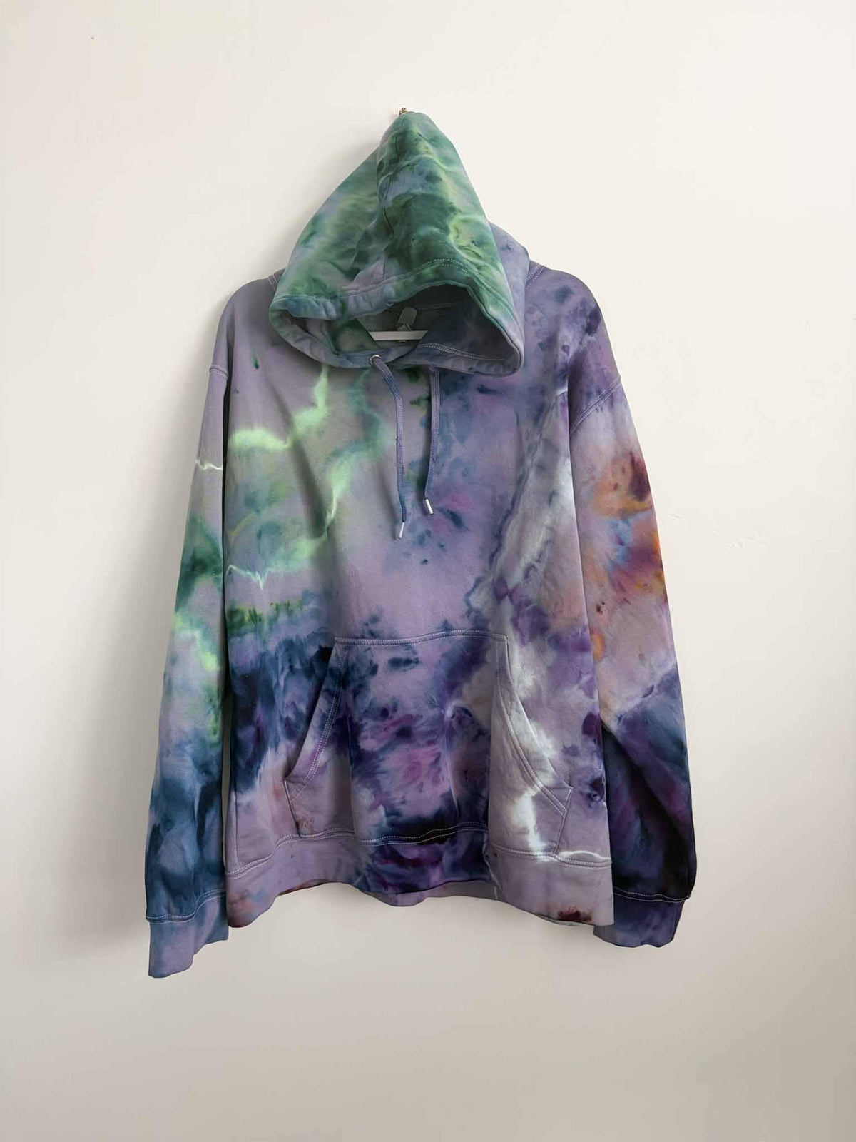XL purple and green ice dye tie dye hoodie hanging, front view, handmade one of a kind