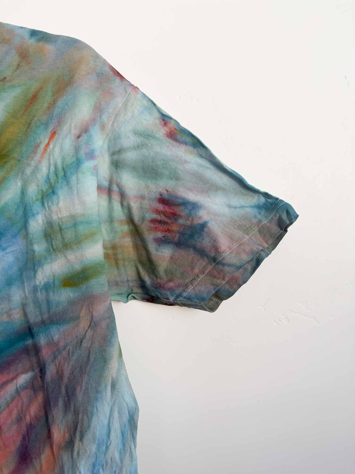 Close up of sleeve on L teal and coral fern fold ice dye tie dye tee