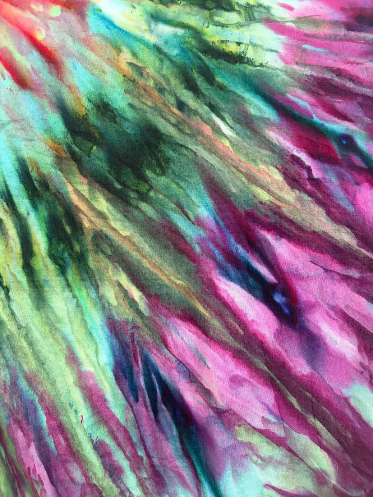 Close up of ice dyed cotton bandana showing green teal and magenta diagonal fan fold tie dye pattern