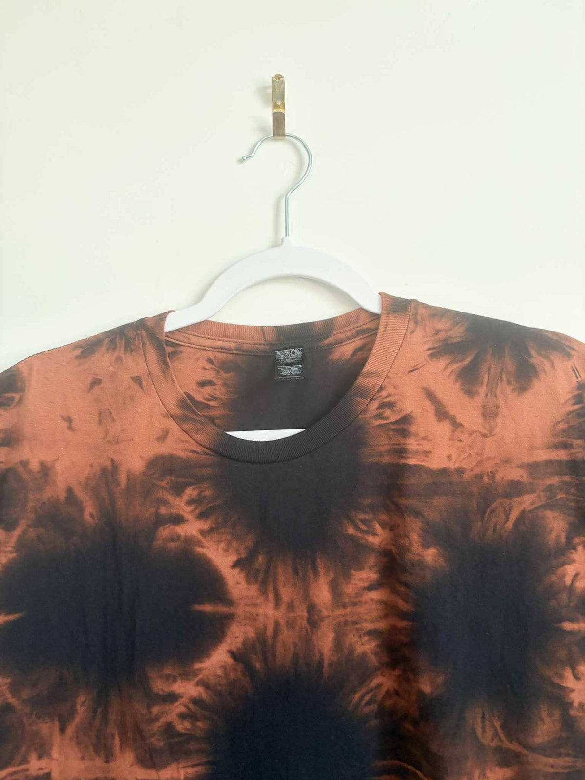 Close up of neckline and collar on black and rust orange shibori bleach tie dye t-shirt