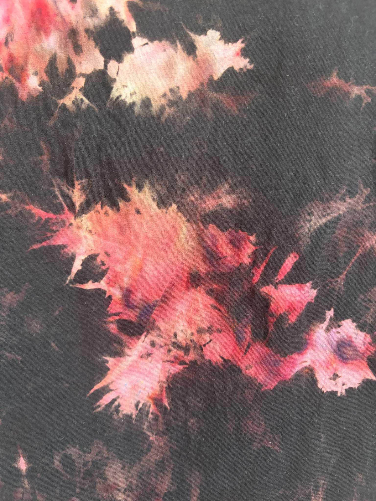 Close up detail of black red and pink bleach crumple tie dye pattern texture on cotton shirt