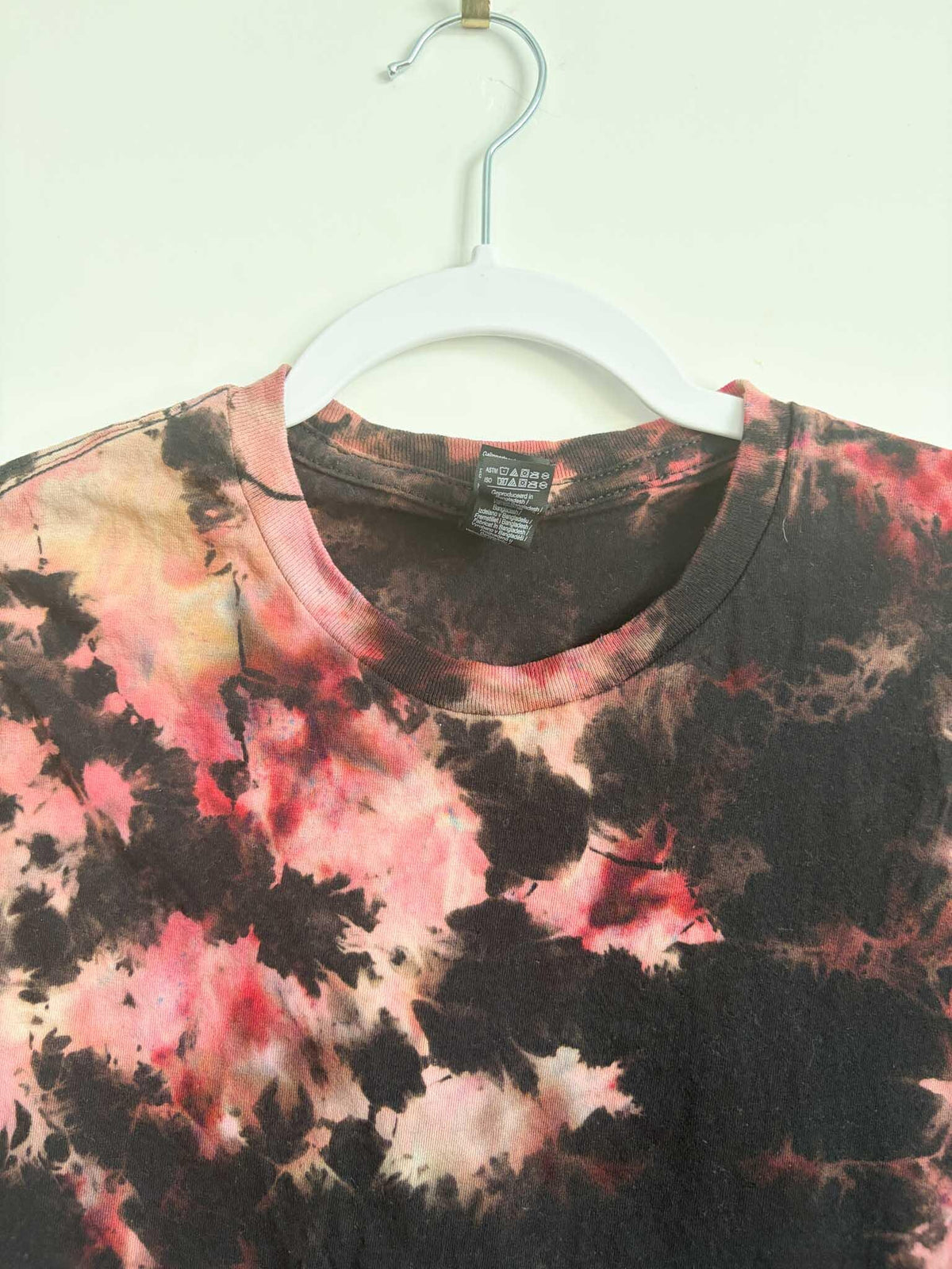 Close up of neckline and care tag on black red and pink bleach crumple tie dye t-shirt