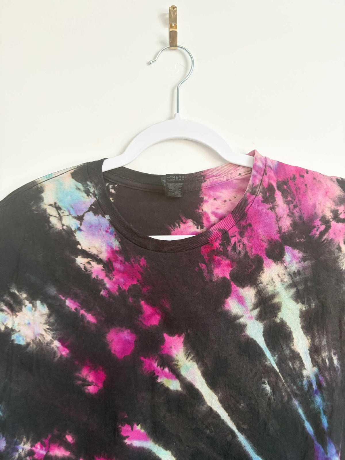 Close up of neckline and collar on black pink purple and blue galaxy spiral tie dye t-shirt