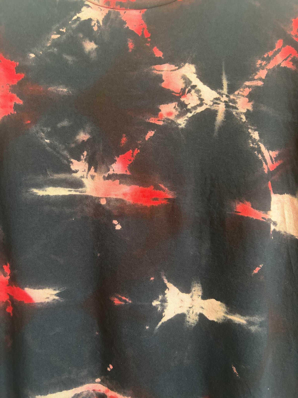 Close up detail of black and red shibori tie dye pattern texture on cotton shirt