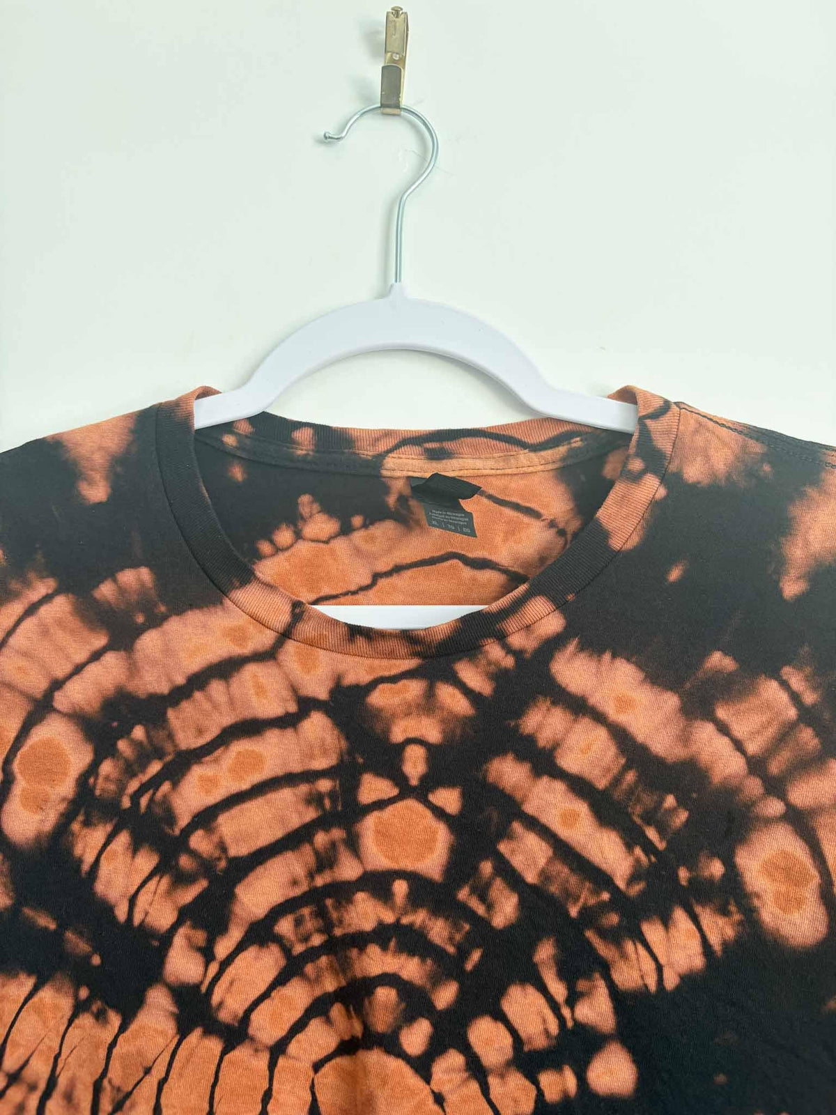 Close-up of reverse tie dye bullseye neckline pattern in rust, copper, and black