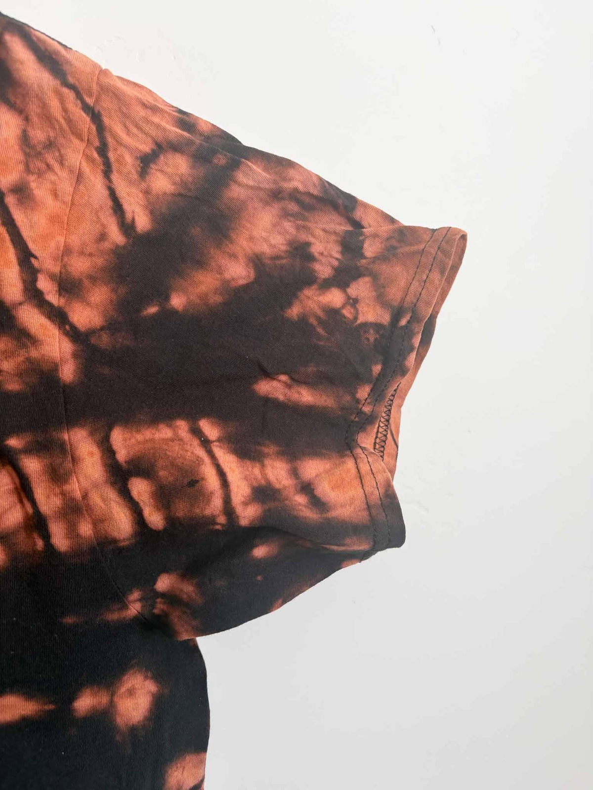 Side view of reverse tie dye shirt sleeve showing bleach-lifted rust and black pattern
