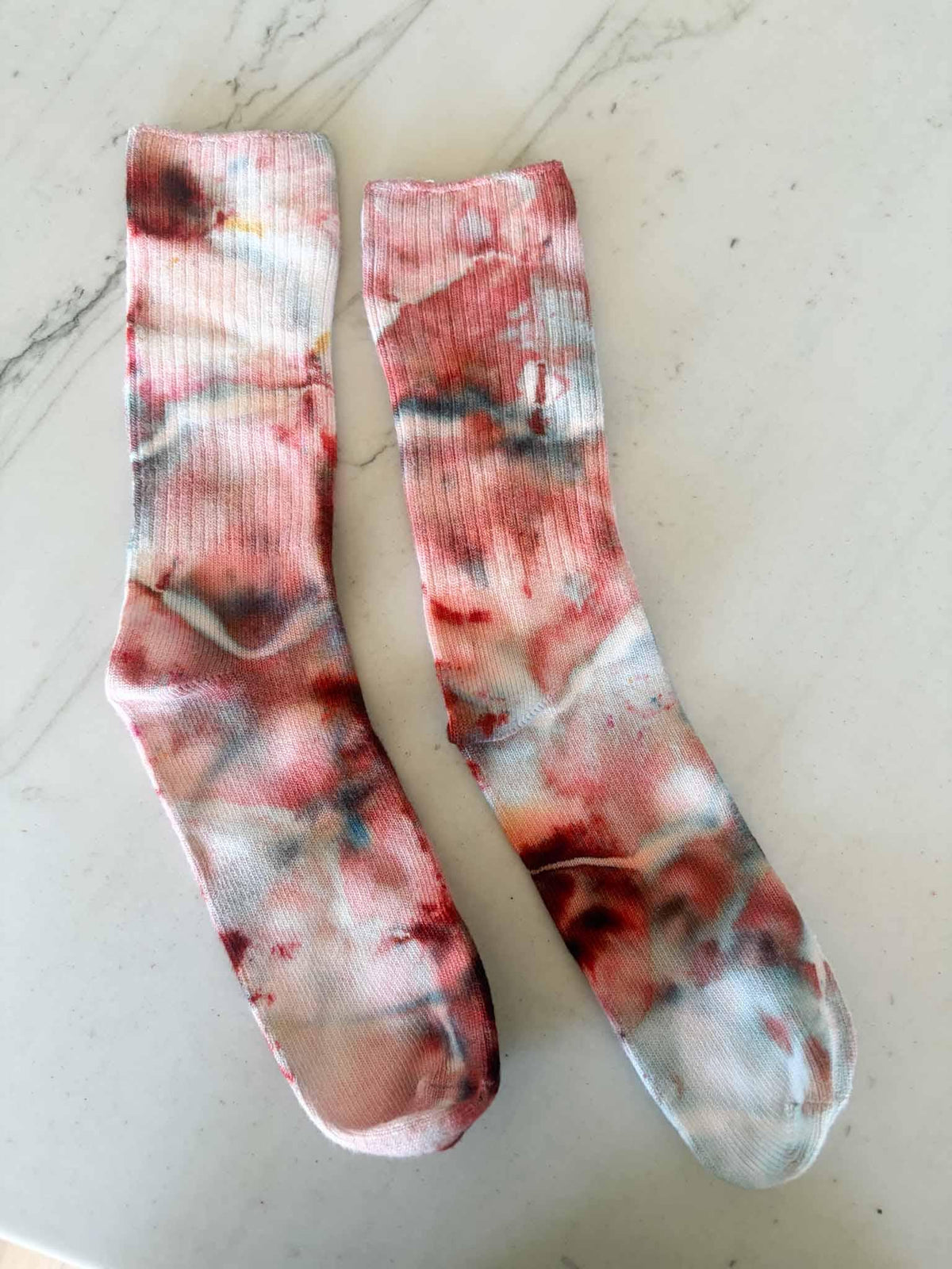 Pair of bamboo crew socks in Bloodmoon tie dye colorway laid flat