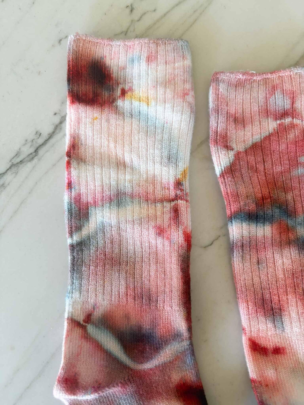 Close-up of crimson, rose, and slate blue ice dye pattern on sock cuffs