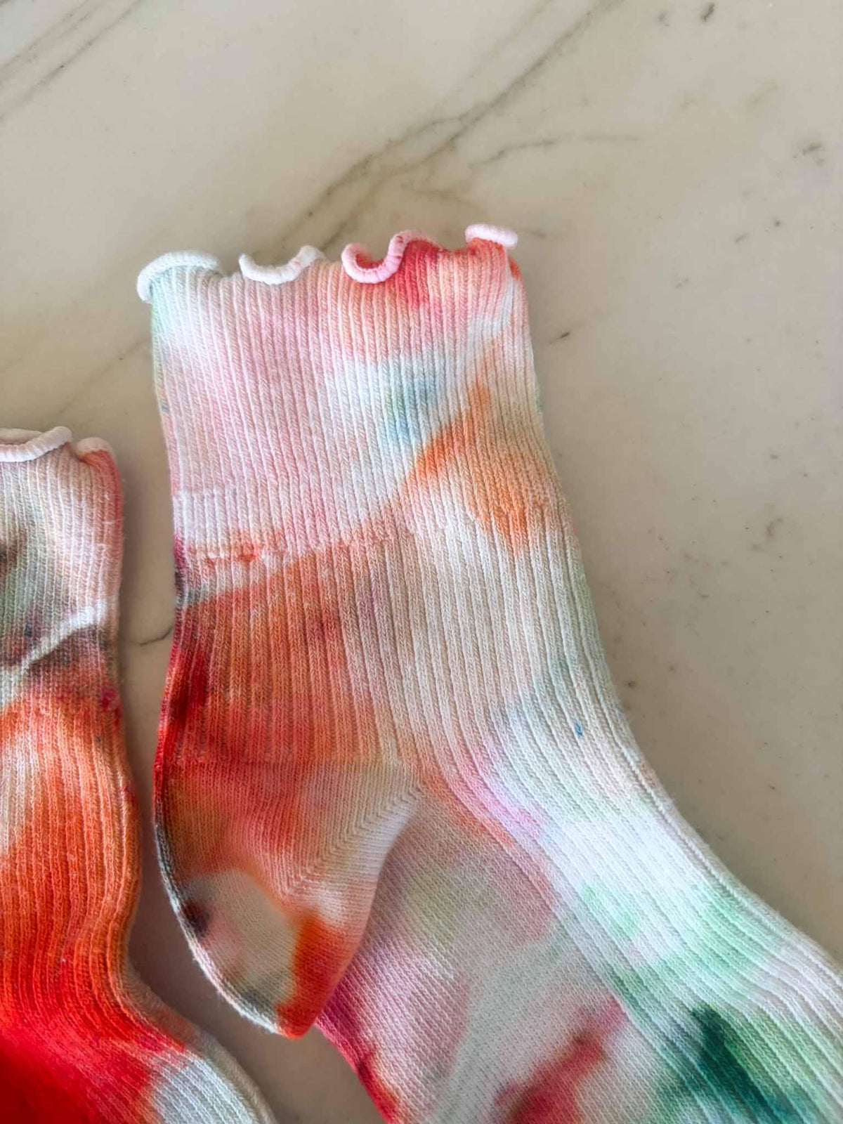 Close-up of ruffle cuff and leg showing coral and seafoam ice dye pattern
