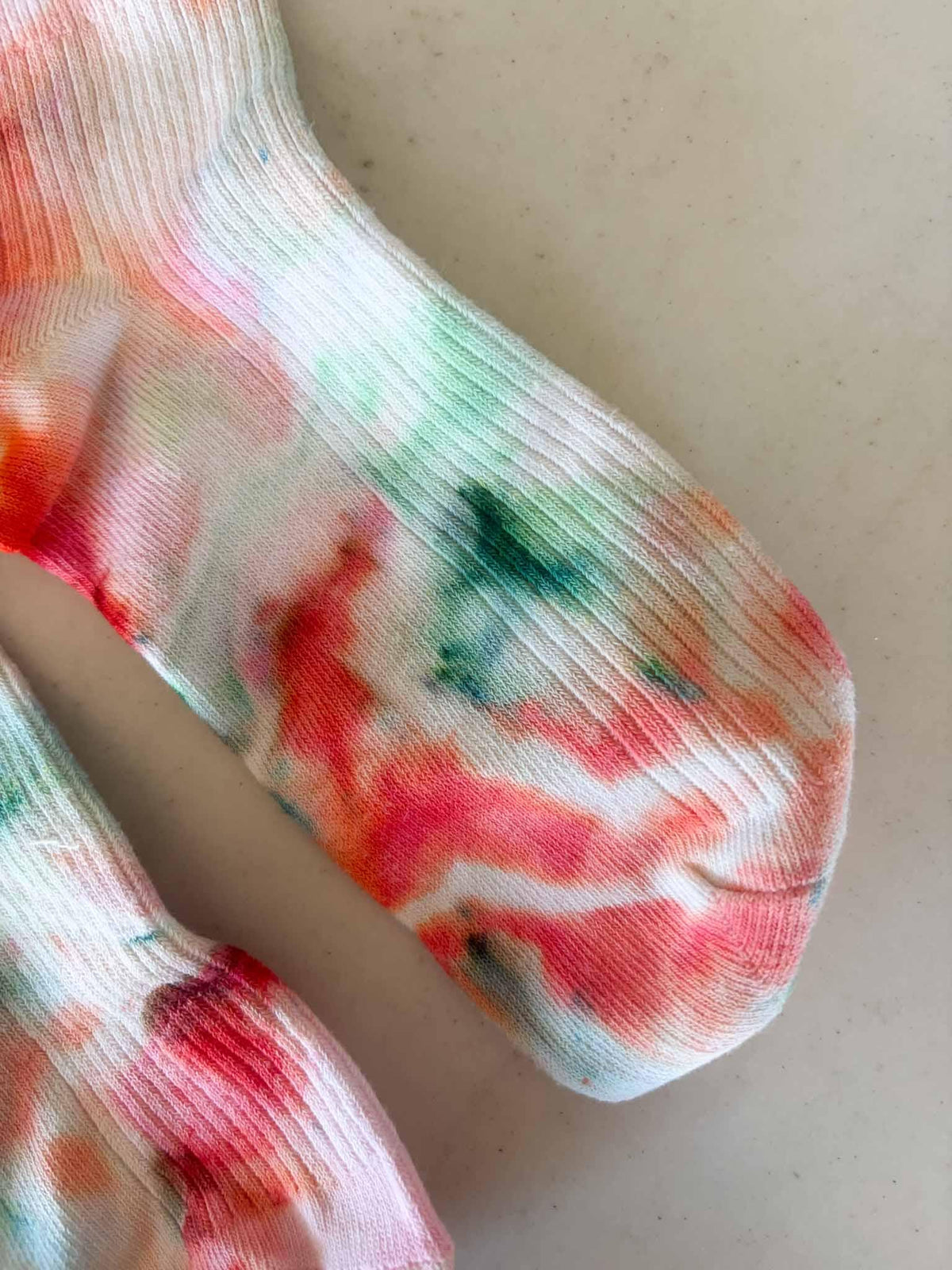 Close-up of ruffle cuff sock toe showing coral, pink, and green watercolor tie dye
