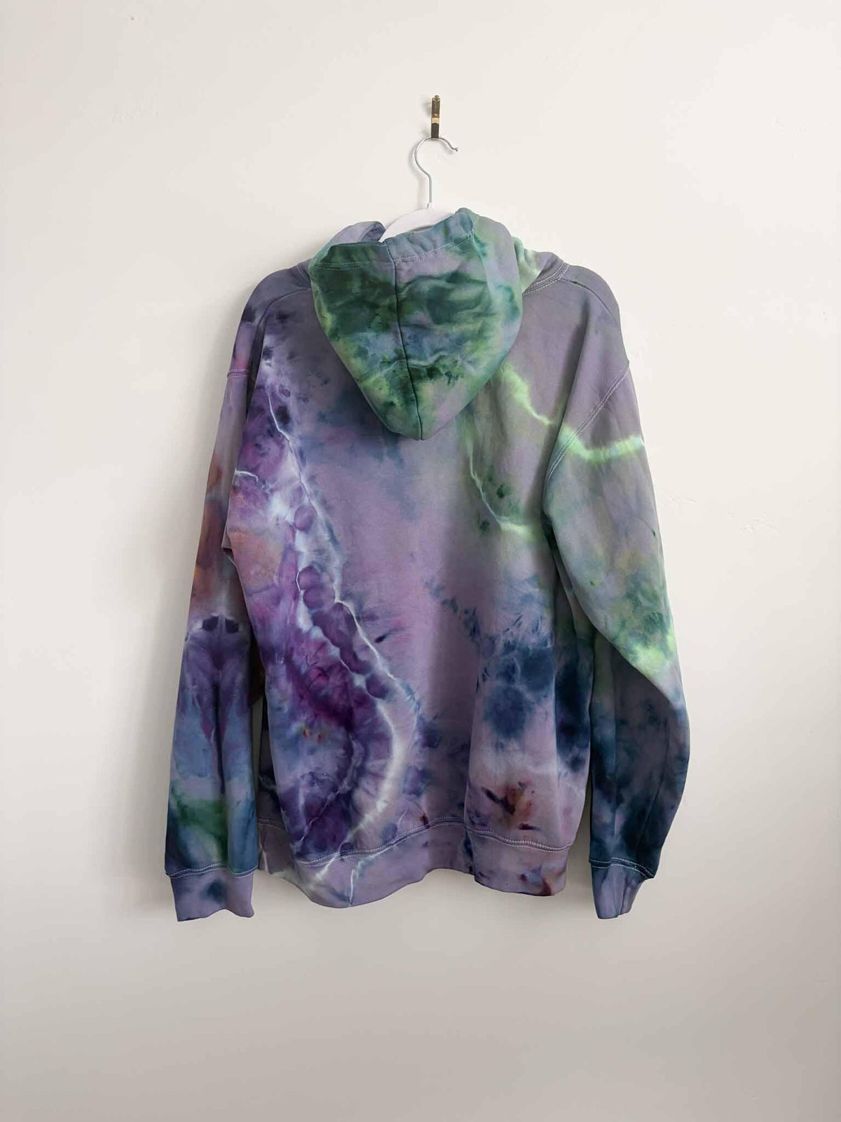 XL purple and green ice dye tie dye hoodie hanging, back view showing hand dyed pattern