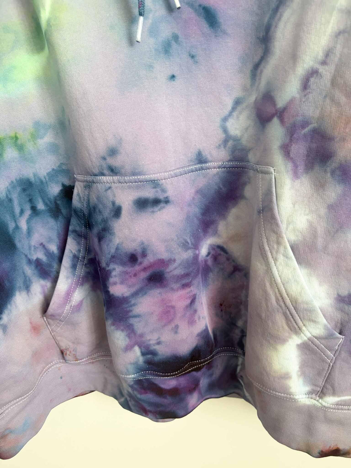 Close up of kangaroo pocket and hem on XL purple tie dye hoodie with ice dye pattern
