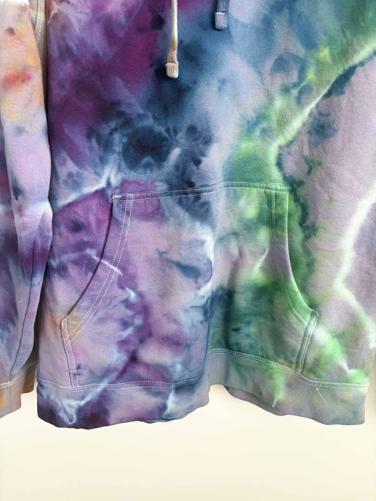 Close up of kangaroo pocket and hem on XL purple green ice dye tie dye hoodie