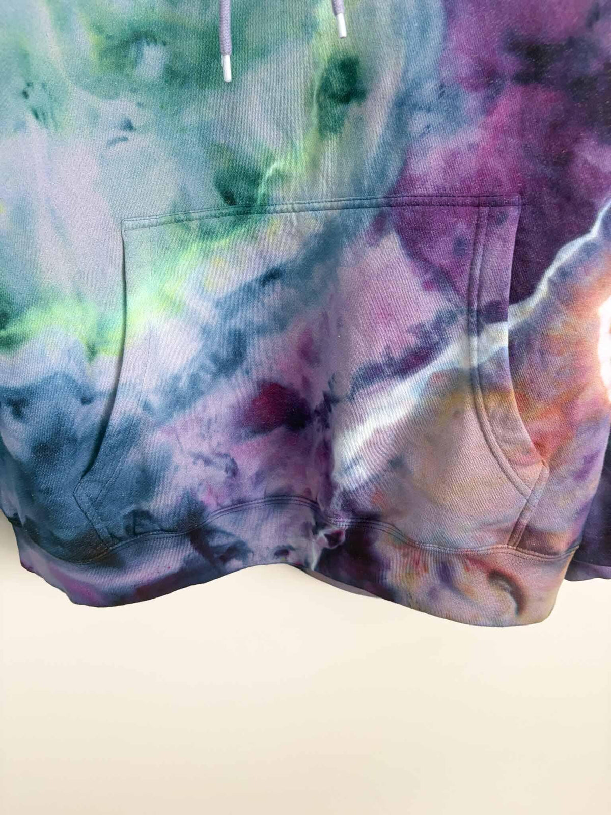 Close up of kangaroo pocket and hem on XL purple and green ice dye tie dye hoodie