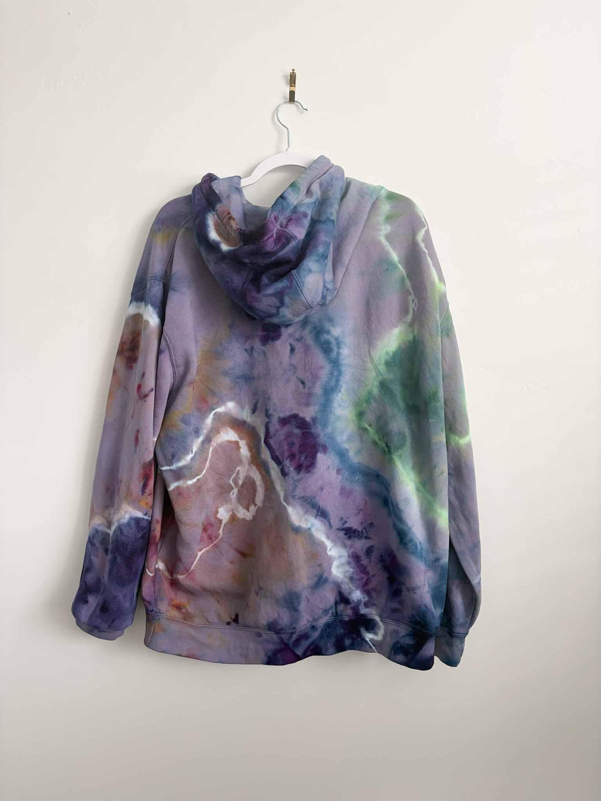XL purple green and gold ice dye tie dye hoodie hanging, back view, handmade one of a kind