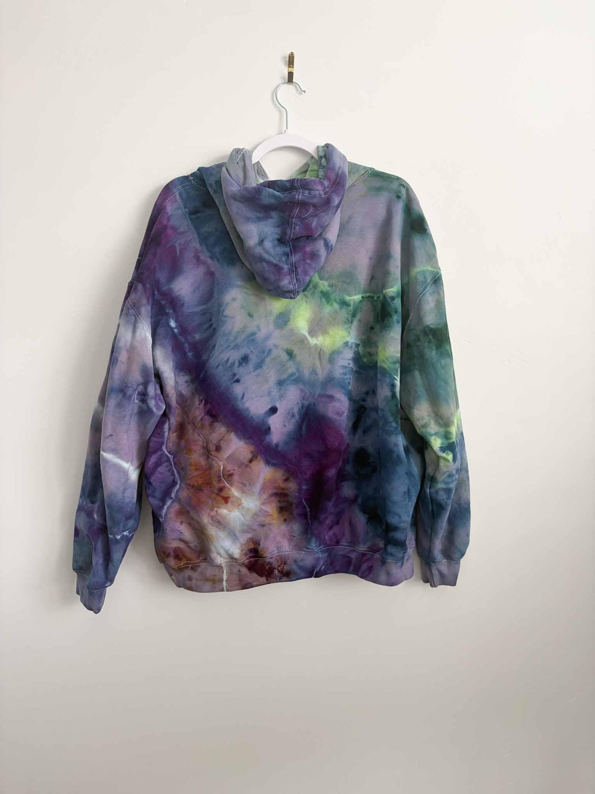 XL purple green and gold ice dye tie dye hoodie hanging, back view, handmade one of a kind