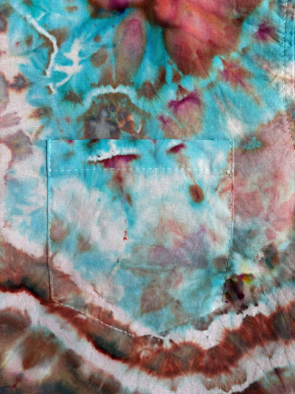 Close up of chest pocket showing turquoise and rust geode tie dye pattern