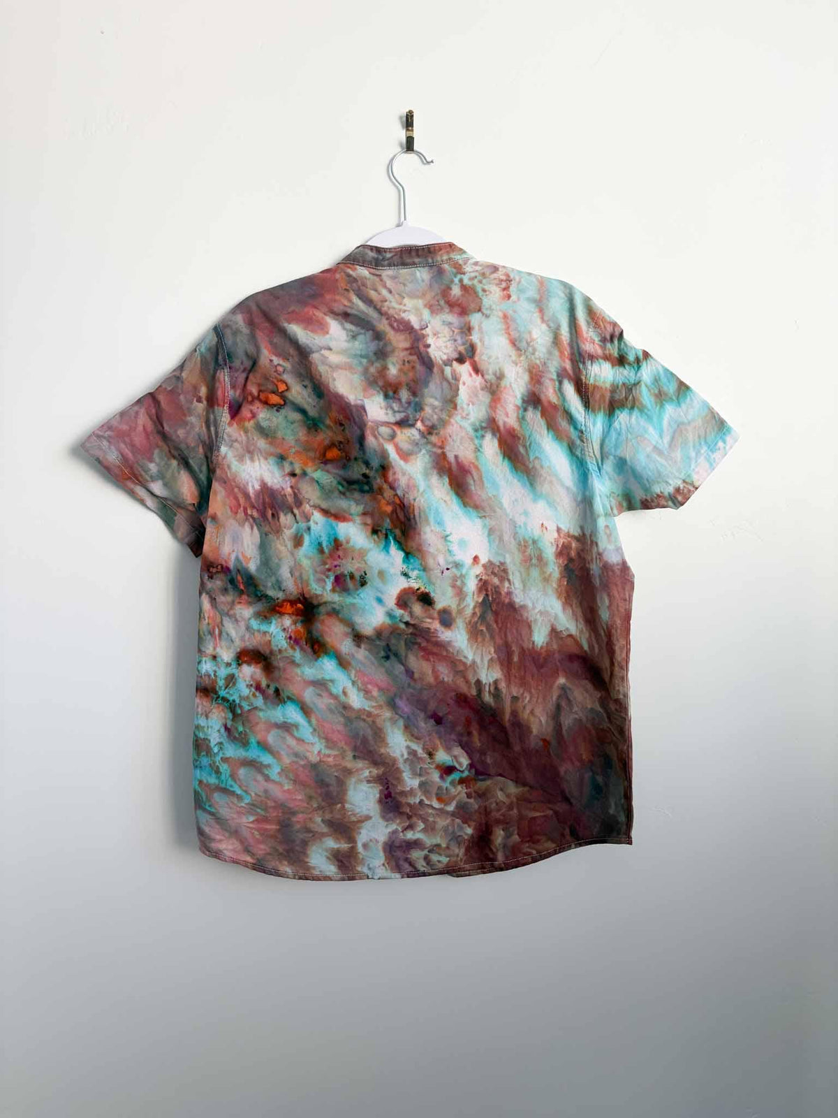 Back view of ice dyed button down shirt showing diagonal turquoise and rust roll fold lines