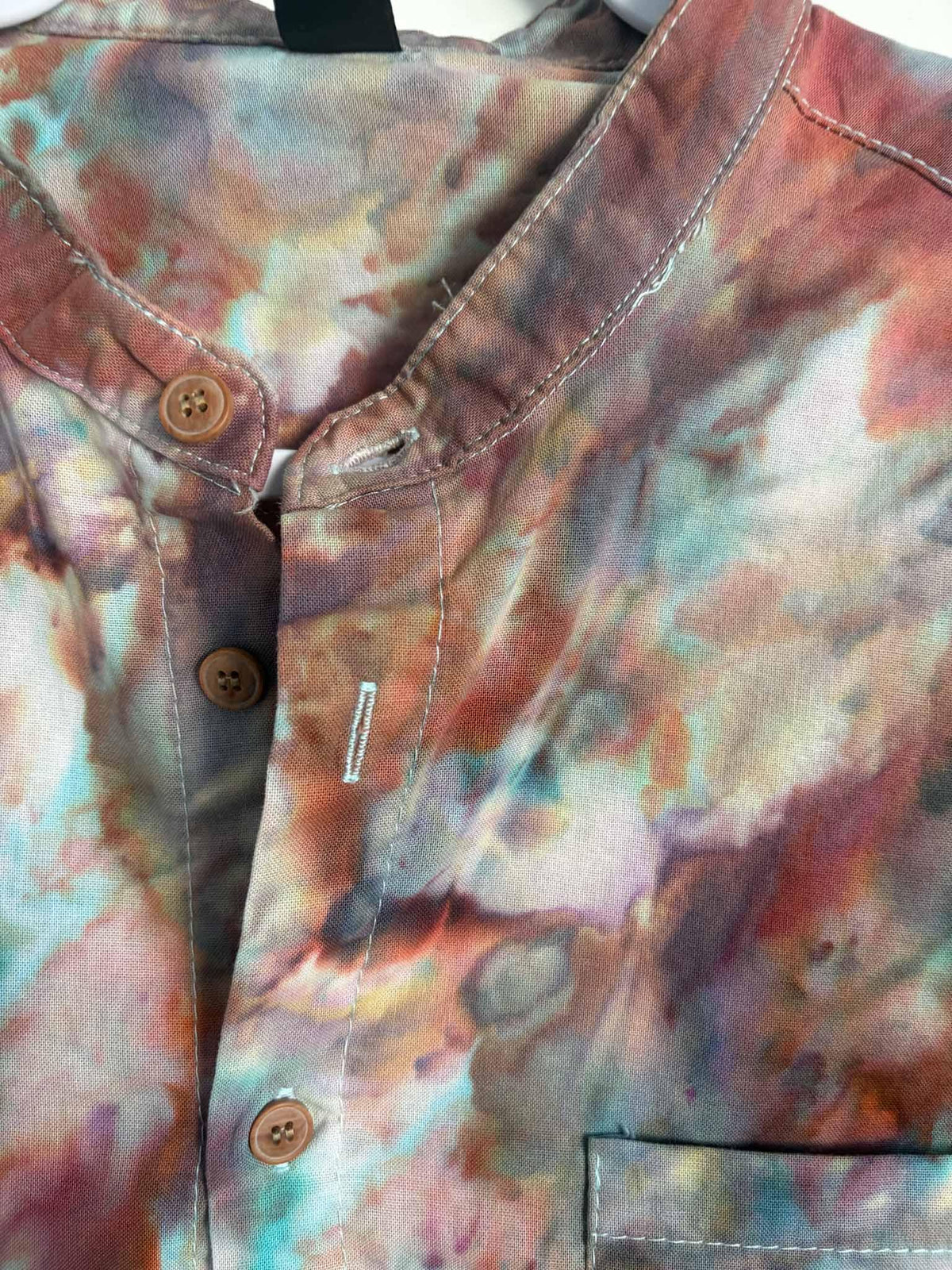 Close up of banded collar and button placket showing turquoise, rust, and brown ice dye colors