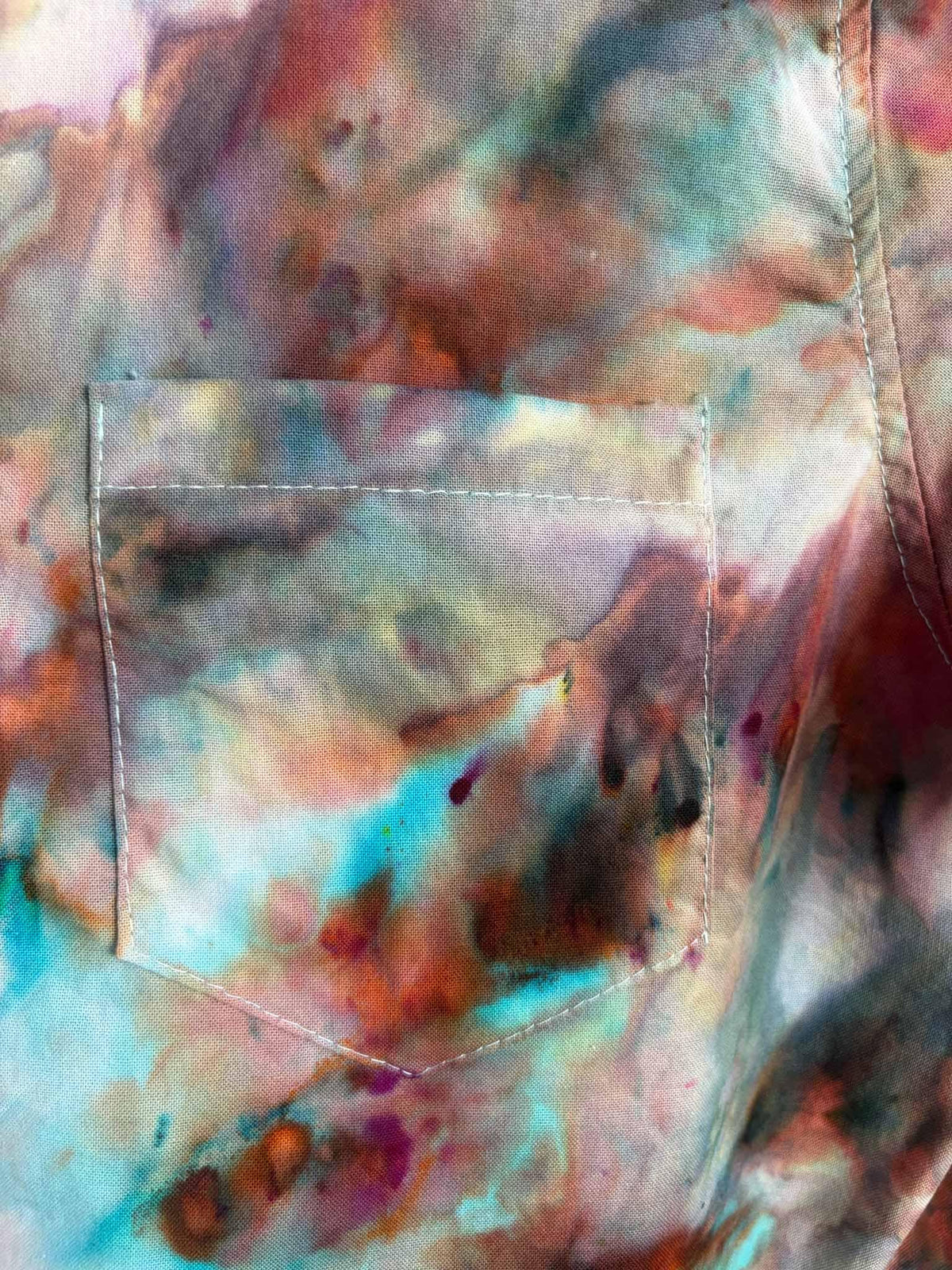 Close up of chest pocket showing turquoise, rust, and pink ice dye color blending