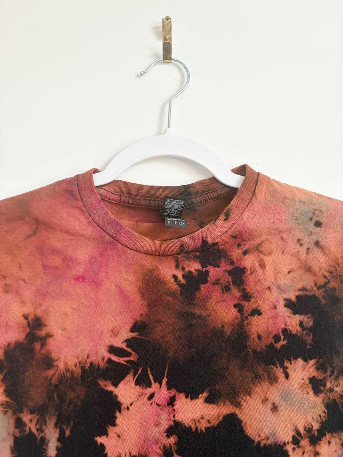 Close up of neckline and collar on black rust and pink bleach crumple tie dye t-shirt