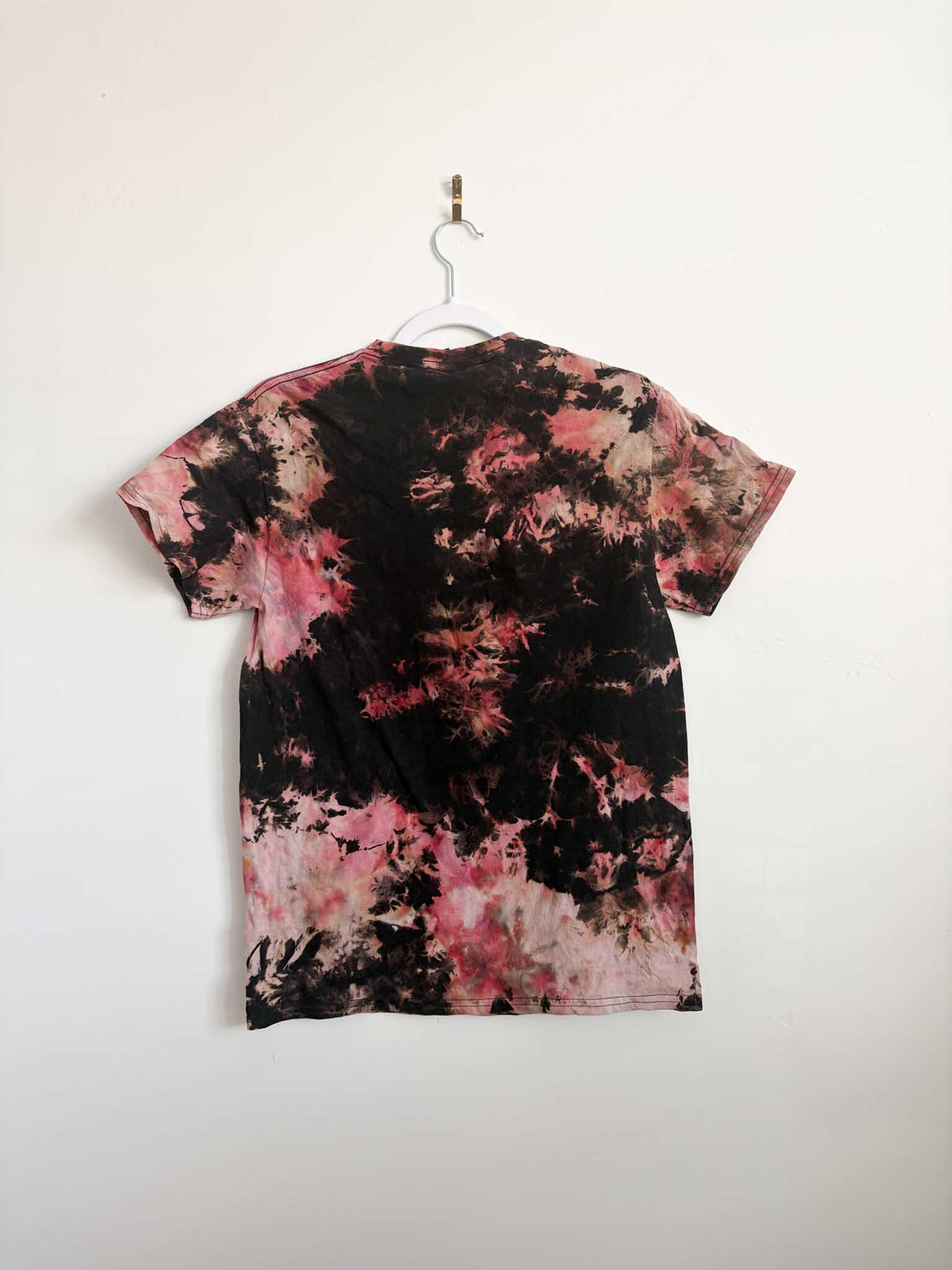 Back view of black red and pink bleach crumple tie dye t-shirt hanging on white hanger