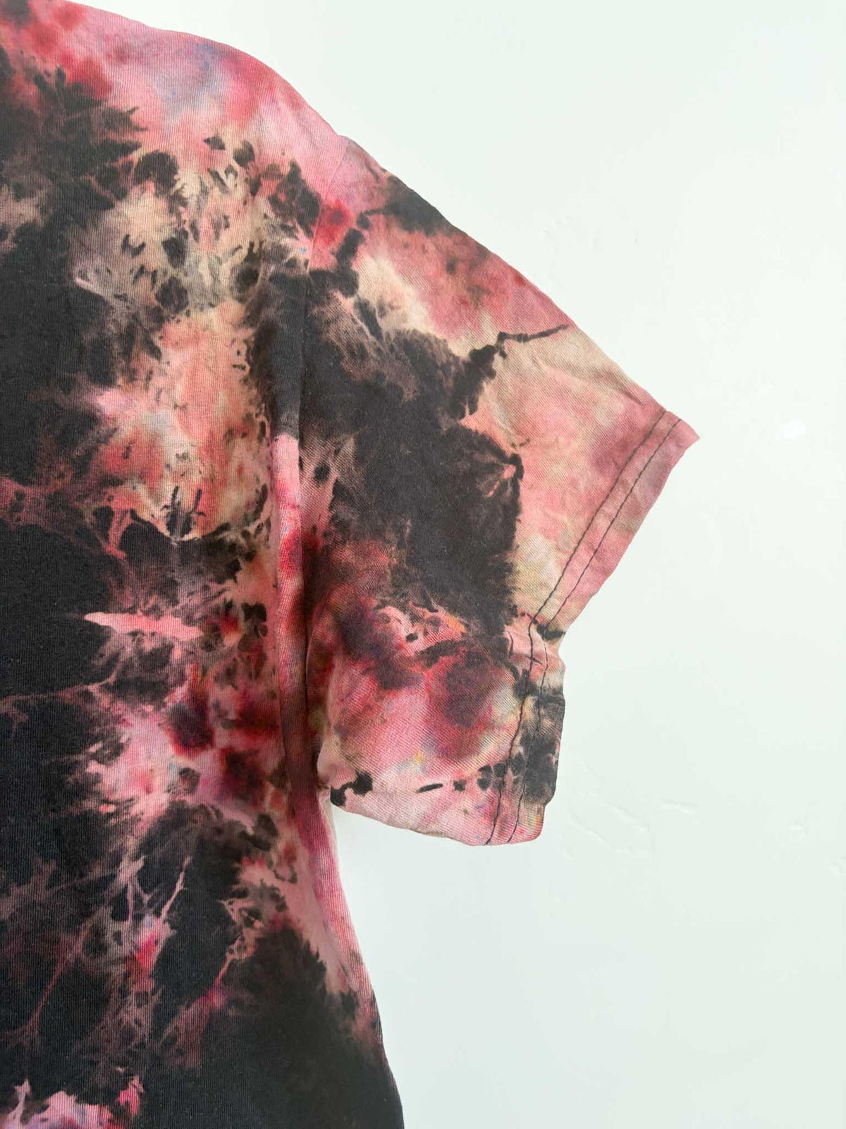 Close up of sleeve and side seam on black red and pink bleach crumple tie dye t-shirt
