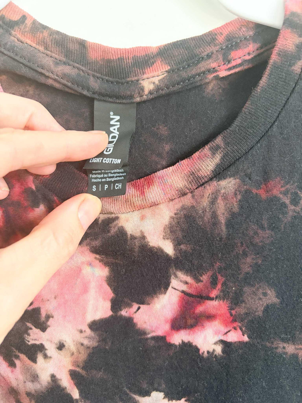 Close up of Gildan Light Cotton size small tag on black red and pink bleach crumple tie dye shirt