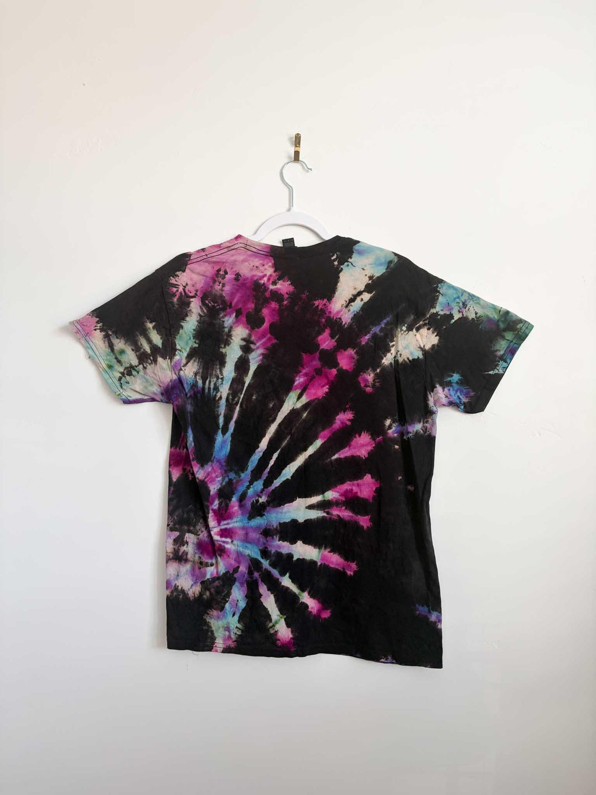 Back view of black pink purple and blue galaxy spiral tie dye t-shirt hanging on white hanger