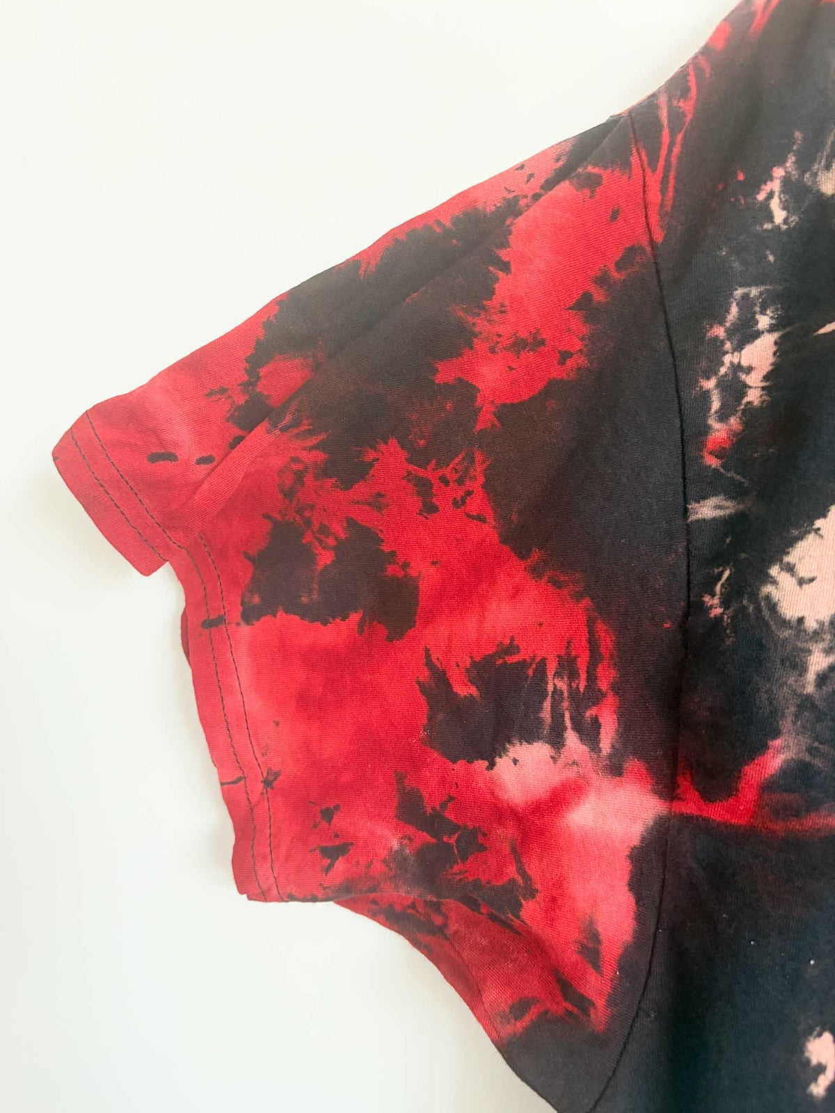 Close up of sleeve and side seam on black and red shibori tie dye t-shirt