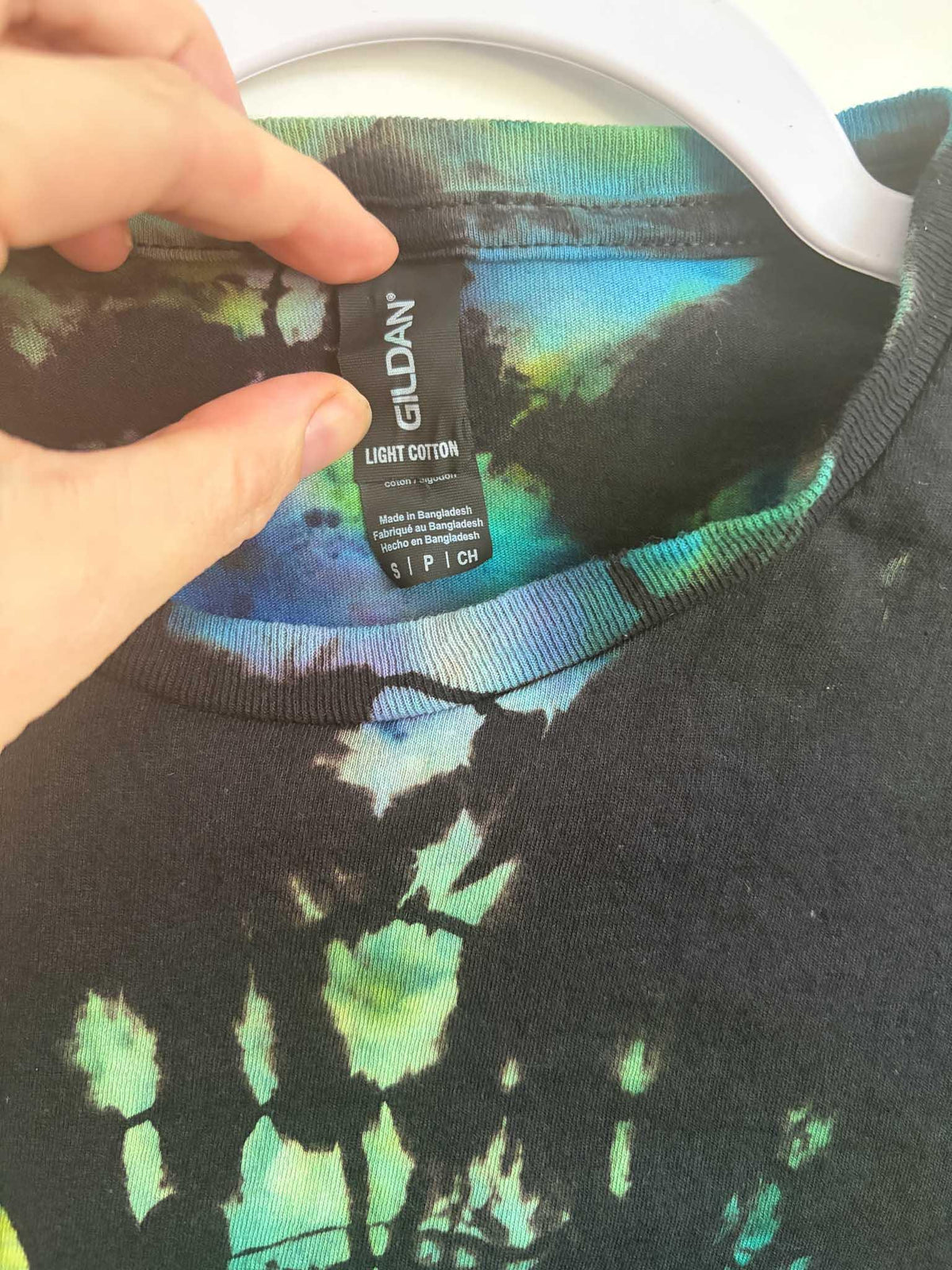 Close up of Gildan Light Cotton size small tag on black and teal ice dye mosaic shirt